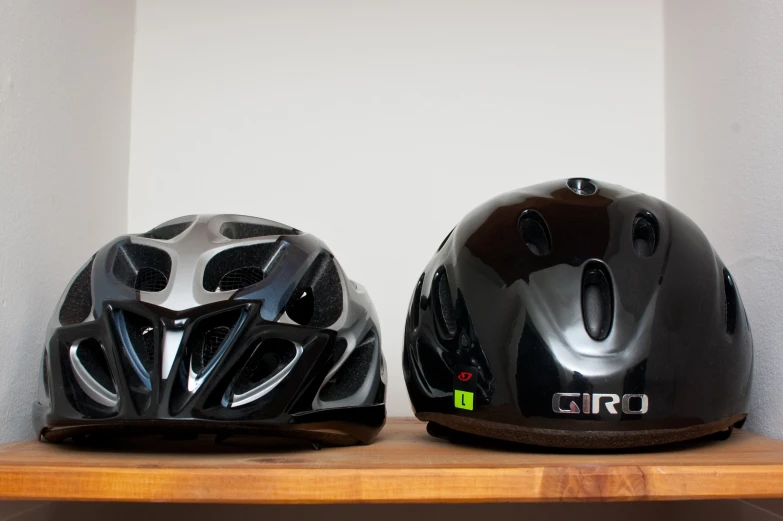 two helmets that are on a shelf and one is black