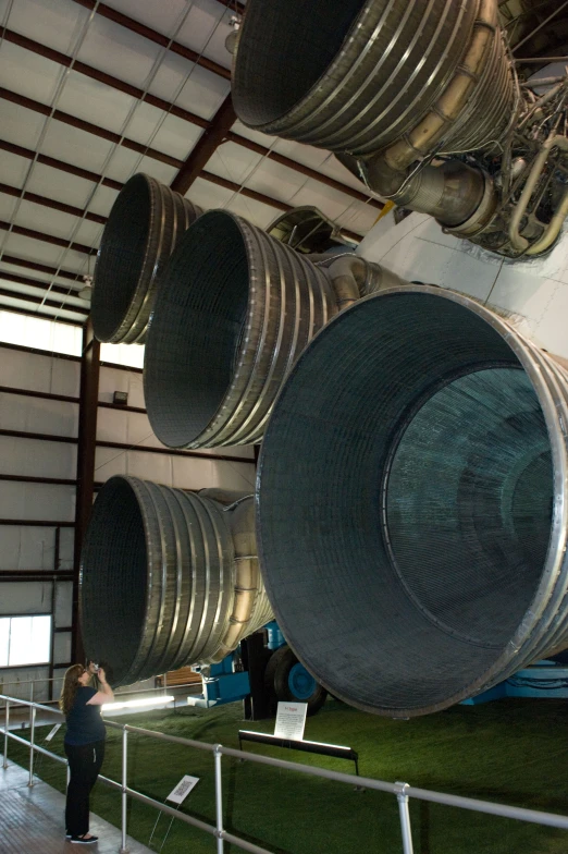 a woman standing by a row of giant metal cylinders