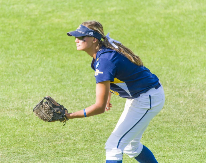 a woman playing baseball in a field is bending her elbow