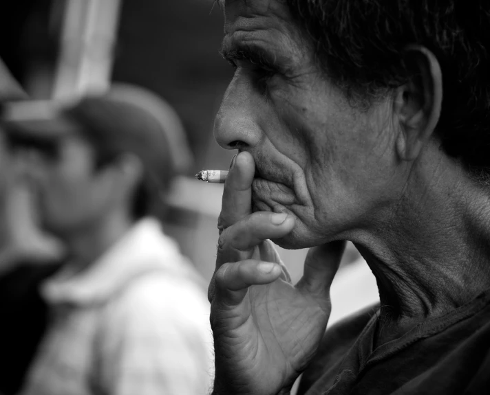 a man smoking a cigarette while another man walks past