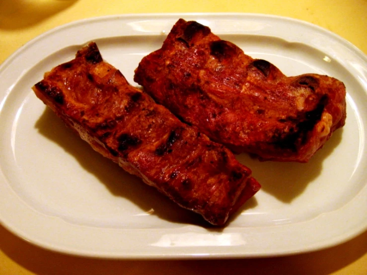 two pieces of meat sit on a white plate