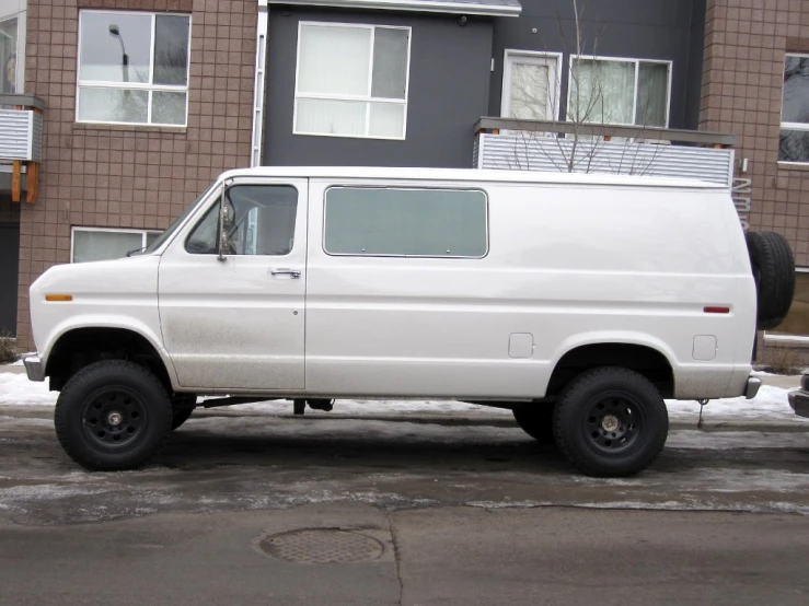 an old white van sits in front of a building