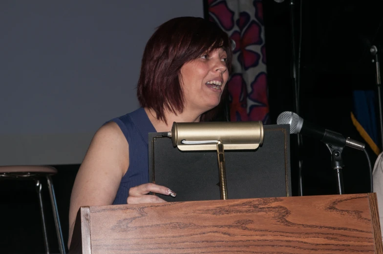 a woman speaking into a microphone next to a podium