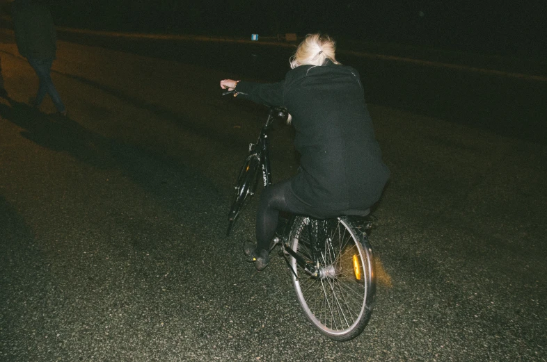 a girl riding a bicycle down the street at night