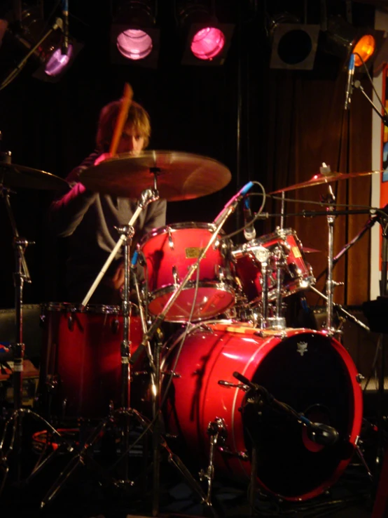 a man playing the drums in front of the stage lights