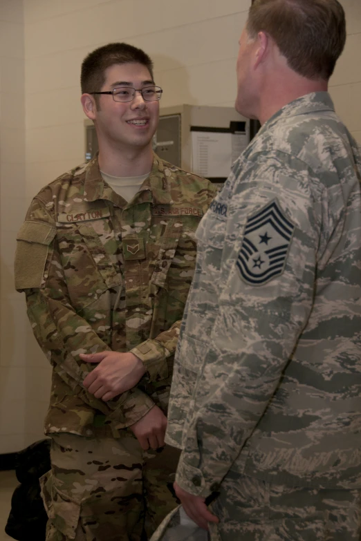 a soldier in fatigues talks to another uniformed man