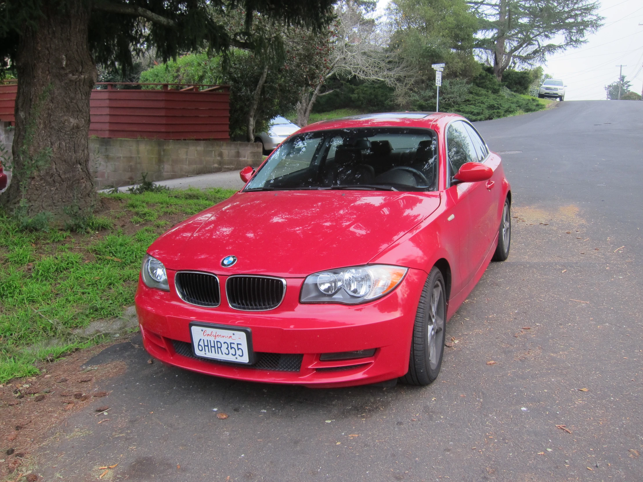 a red bmw is parked on the street in a driveway