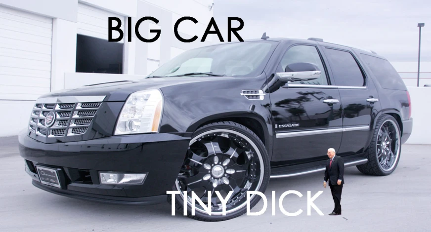 a man in a suit standing next to an suv with huge wheels