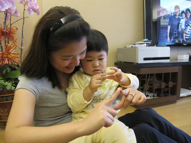 a woman and child sitting on a floor next to a television