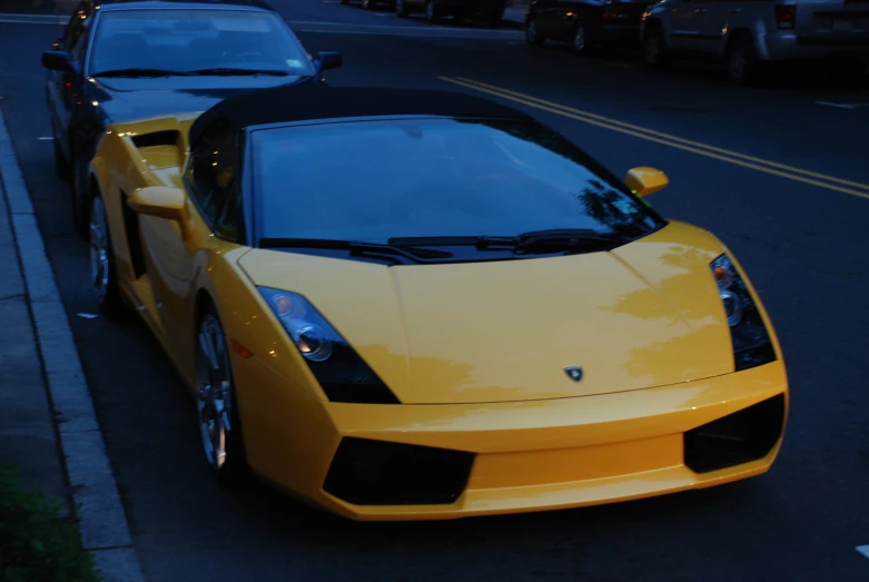 the yellow and black sports car is parked next to the curb