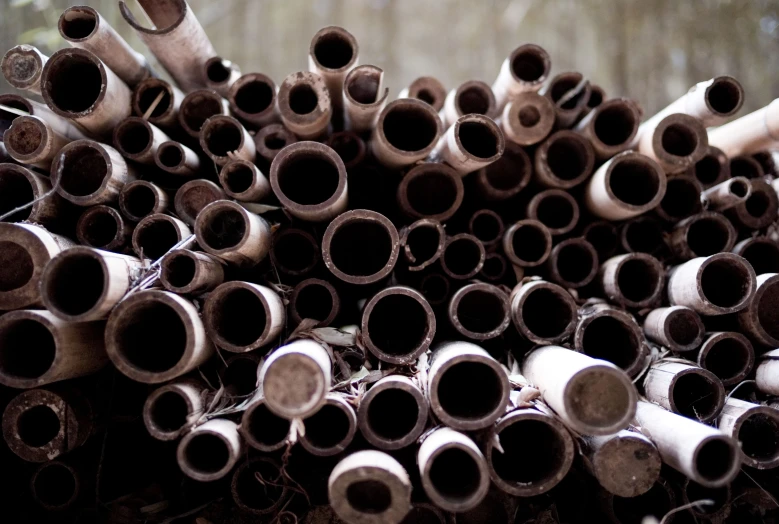 a large pile of old, dirty pipes stacked on top of each other