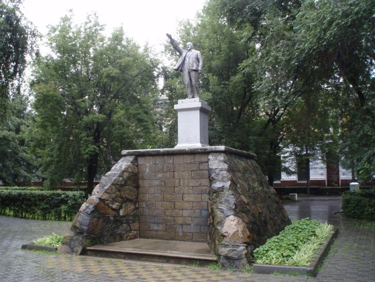 a statue in the middle of a square, surrounded by trees