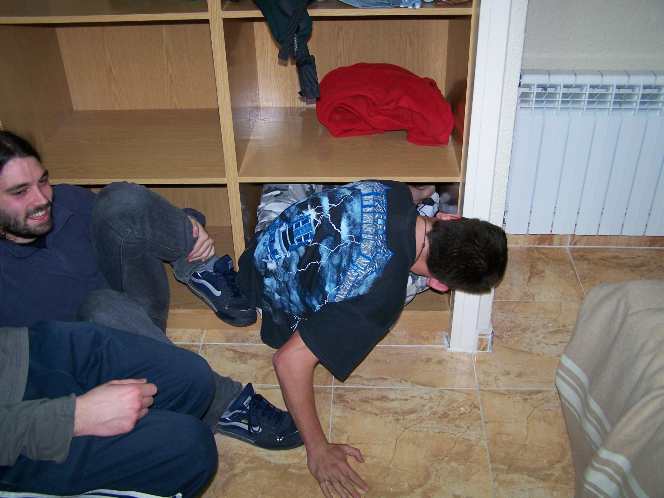 two people are sitting on the floor under a book shelf