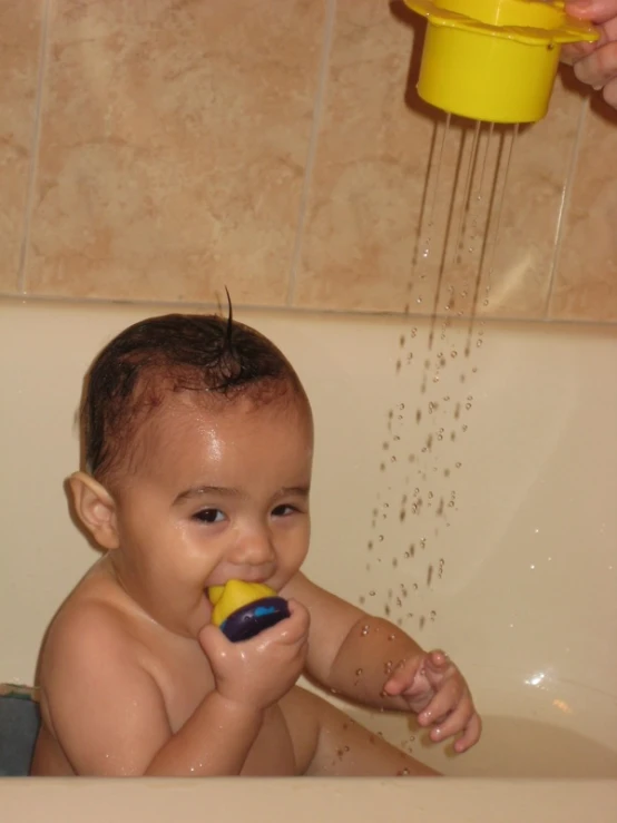 a baby is sitting in the bathtub playing with the toys