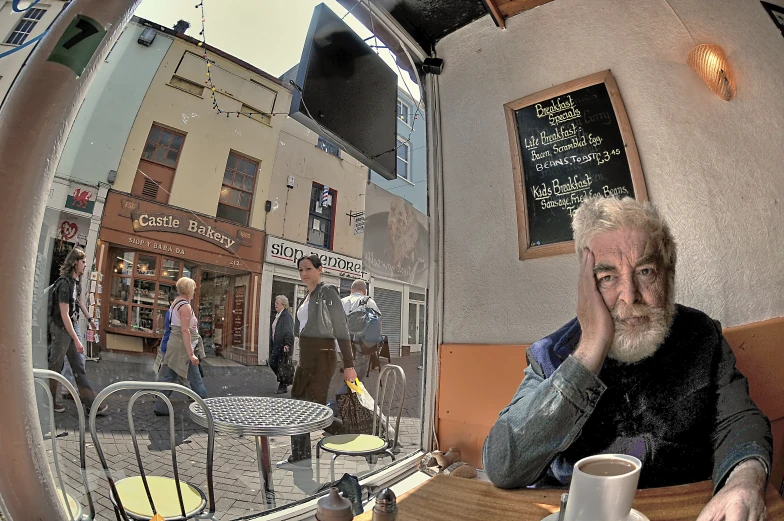 a man sitting at a table with his reflection in the mirror