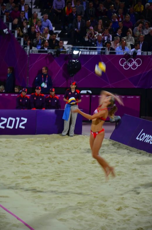 a woman playing volleyball while people watch