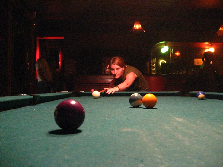 a woman leaning down to take a s at pool balls