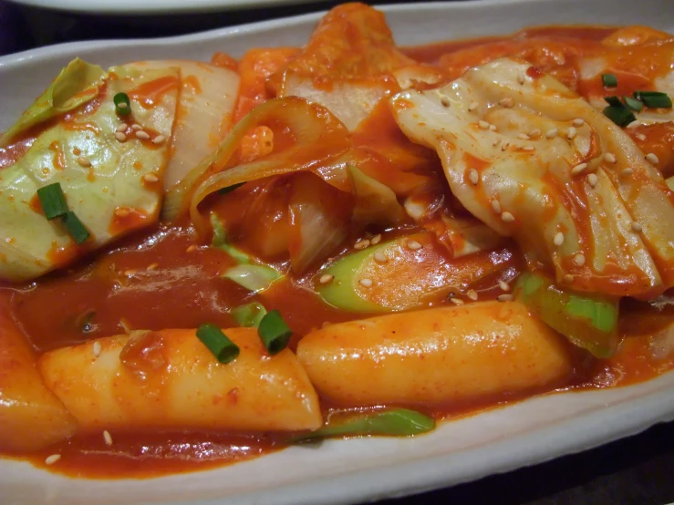 a white plate topped with vegetables covered in sauce