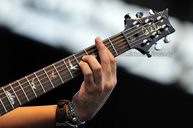 a person with their hands on the strings of a guitar