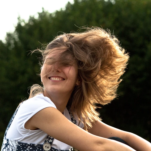 a girl sitting on the ground with her hair blowing in the wind