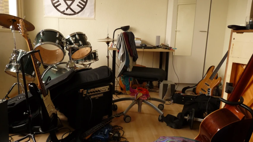 an assortment of drums and bass heads sit in a cluttered room