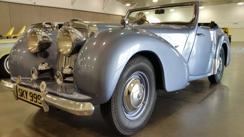 an old model grey car on display in a building