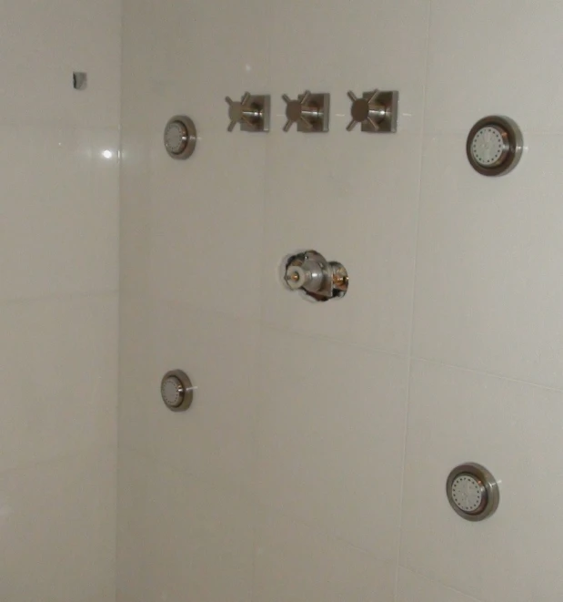 a shower with various faucets and hands