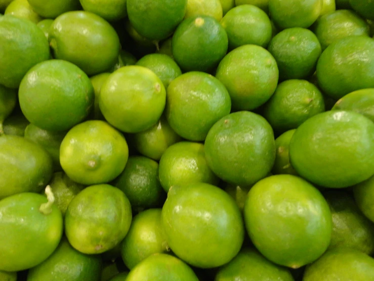 the green limes are arranged neatly in a pile