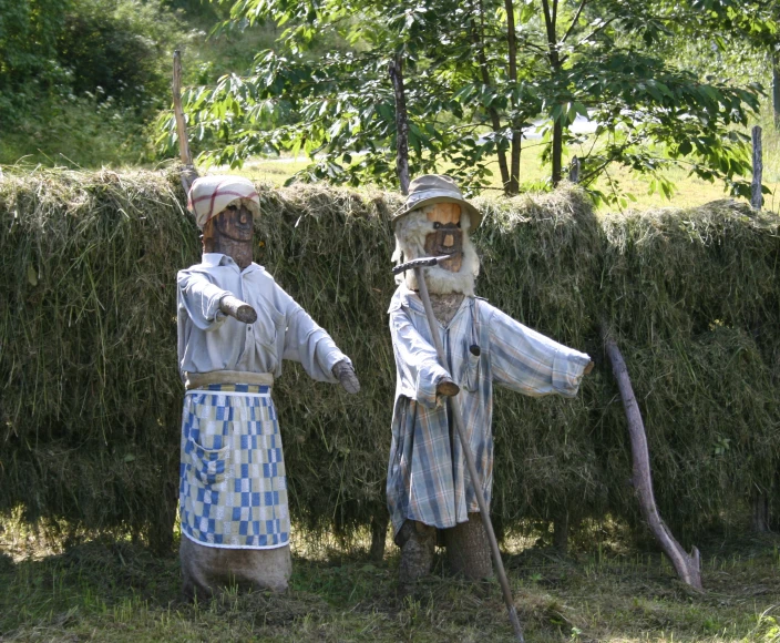 two statues dressed as farmers are in front of some hay bails