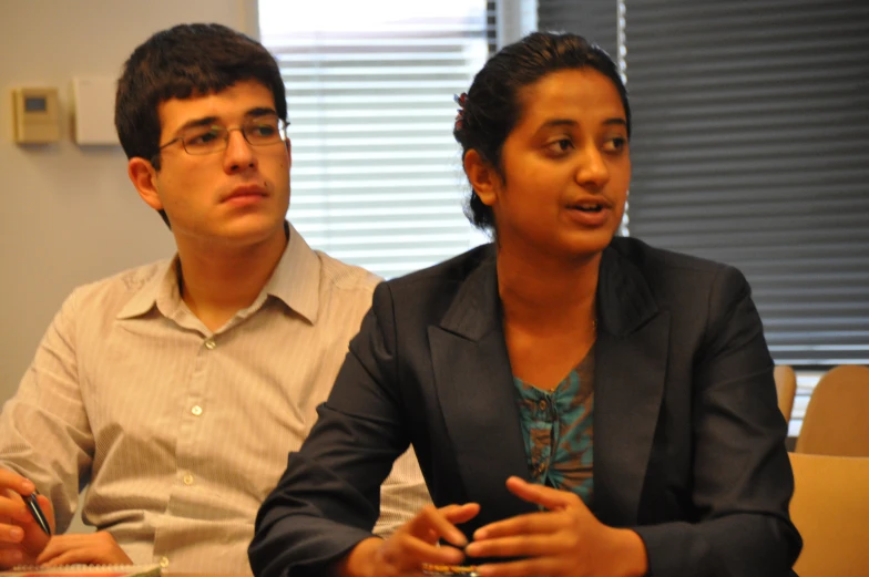 man and woman sitting at table in office setting