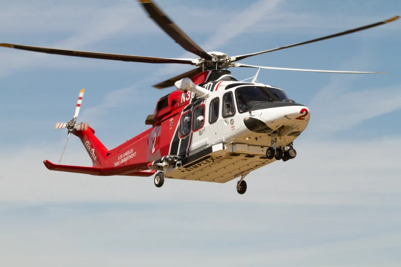 a white and red helicopter flying across a blue sky