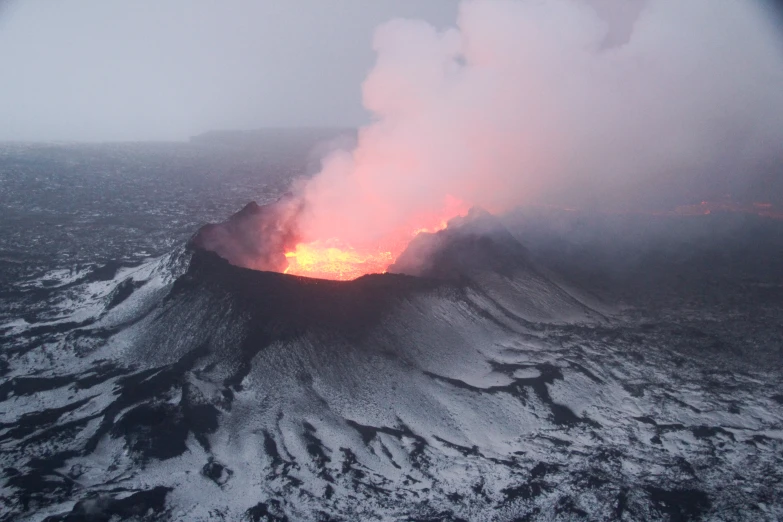 a volcano erupts lava and light ash in the atmosphere