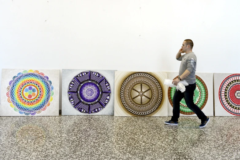 man walking by artwork in front of white wall