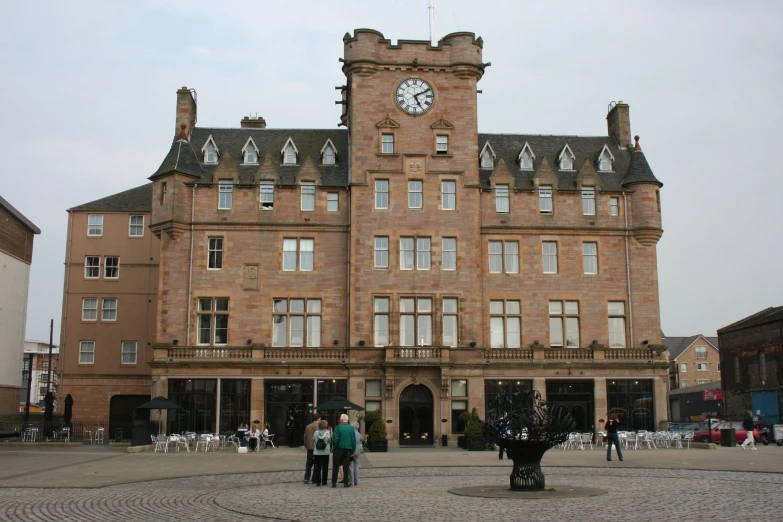 people standing in front of a tall building with a clock