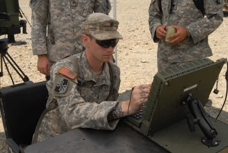 a military man in camouflage working on a laptop