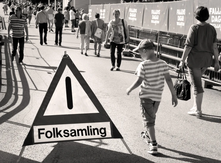 a  walks through a street past a traffic sign warning folks about following him