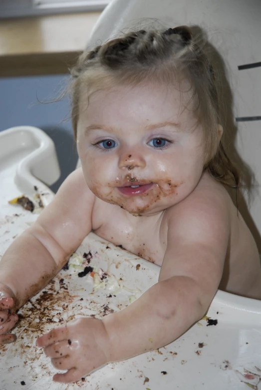 a young baby sits in a high chair full of food