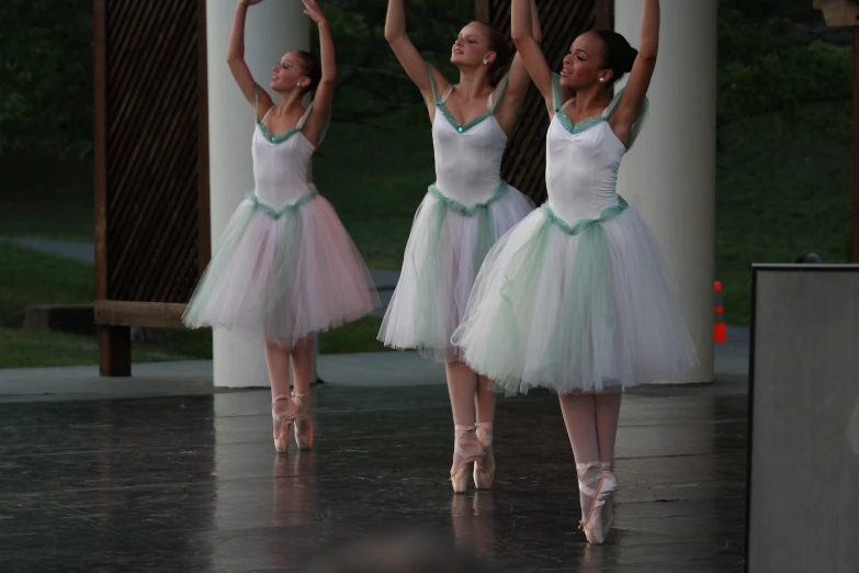 four women in white and green tutu skirts posing with arms up