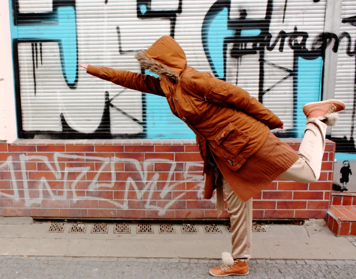 a woman standing on one leg in a city alleyway