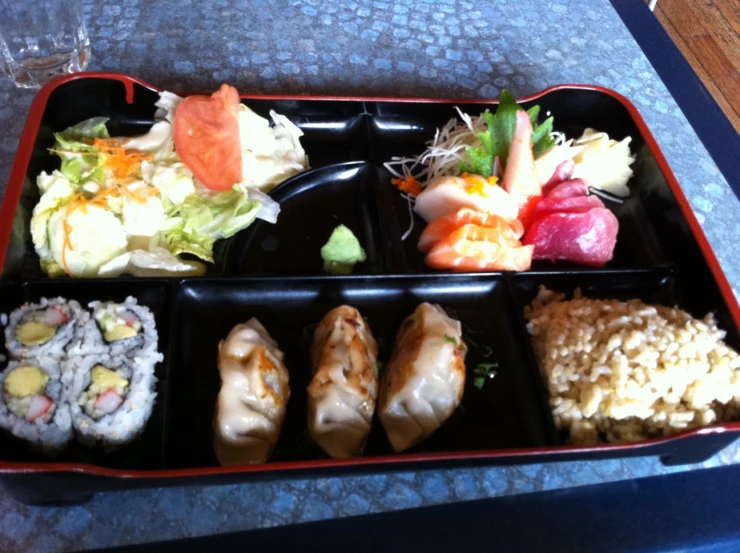 a red plate holding rice rolls and vegetables