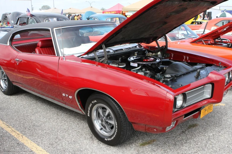 a red muscle car is showing its hood open and it's engine