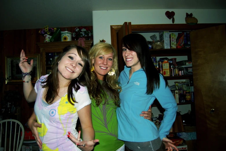 three girls in a kitchen with their hands up