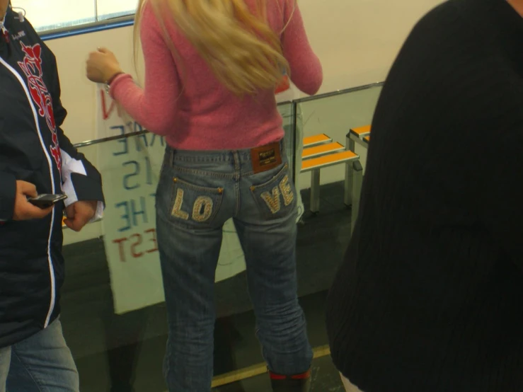 a person wearing jeans and high heels stands by the glass wall