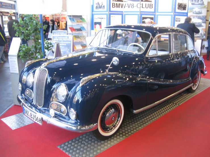 a blue classic car is on display at a convention