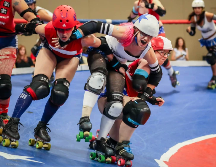 a group of roller blades in action on a blue and white court