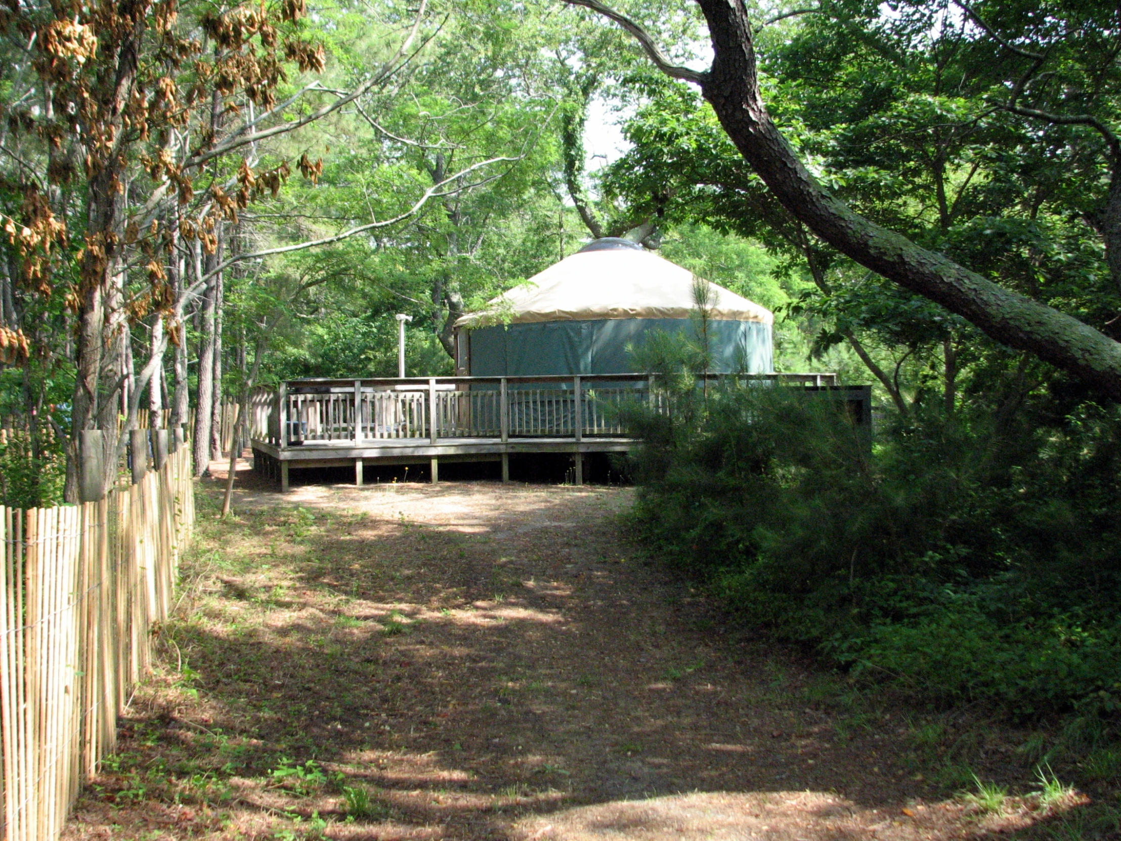 a yurt set sits behind a wooden fence in the woods