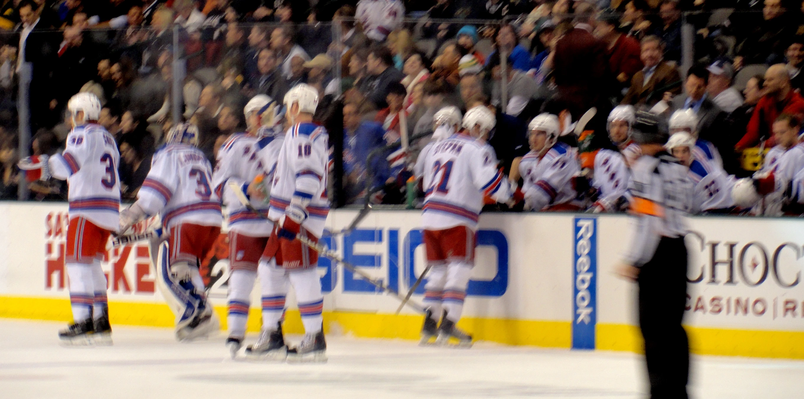 a number of men on the ice, with a referee behind them