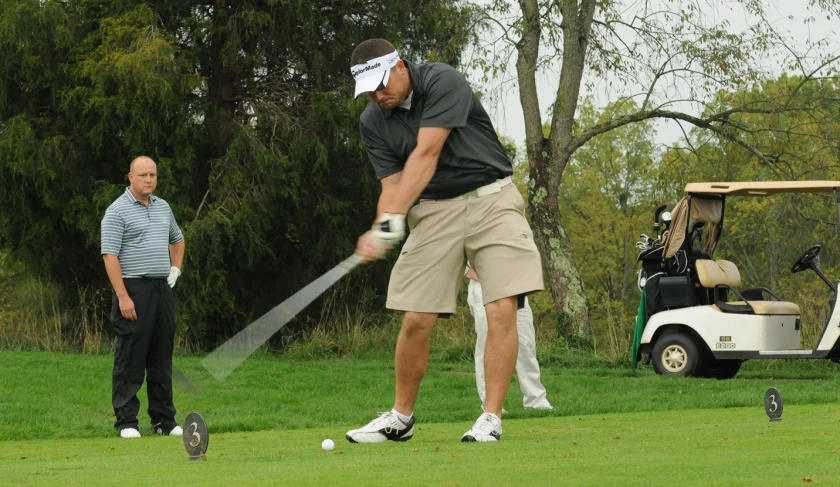 two people playing golf and another man is in the background on the grass