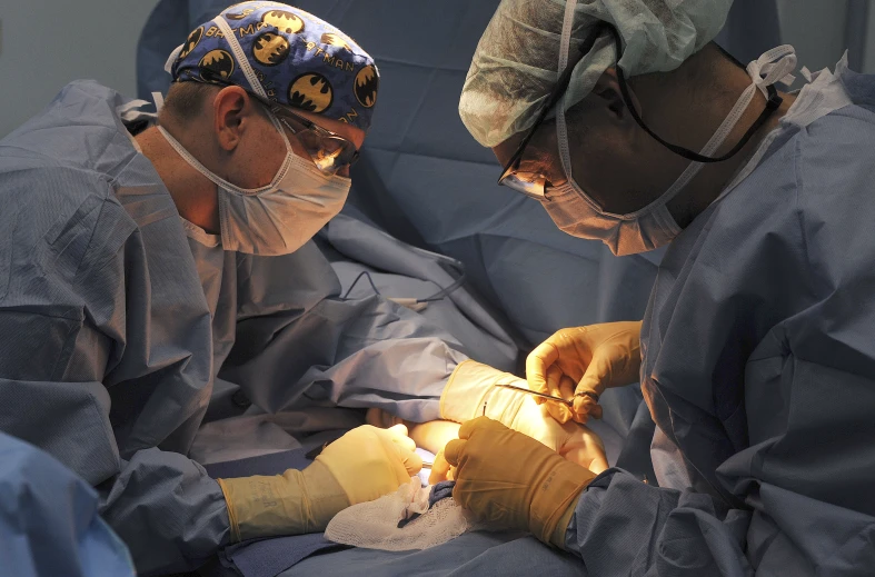 two men wearing protective gloves are working on a baby