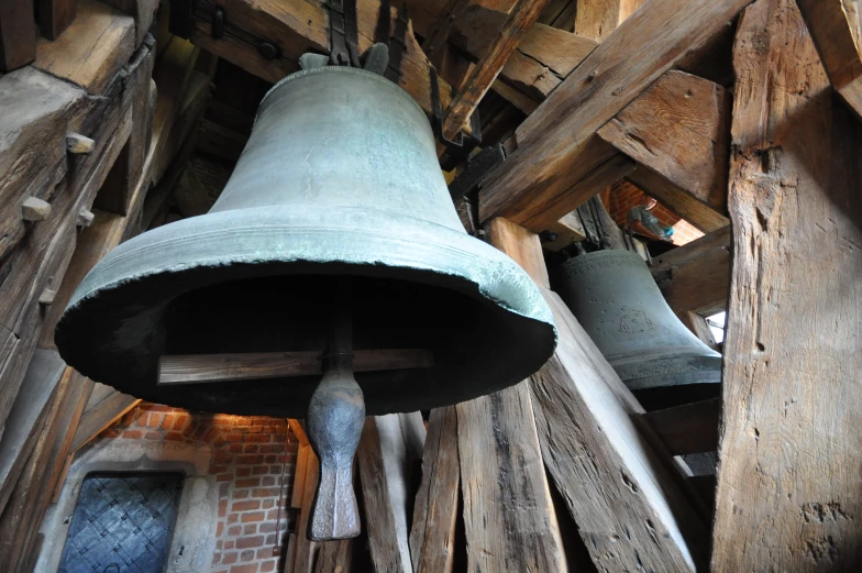 an old metal bell on wooden structure with wood beams